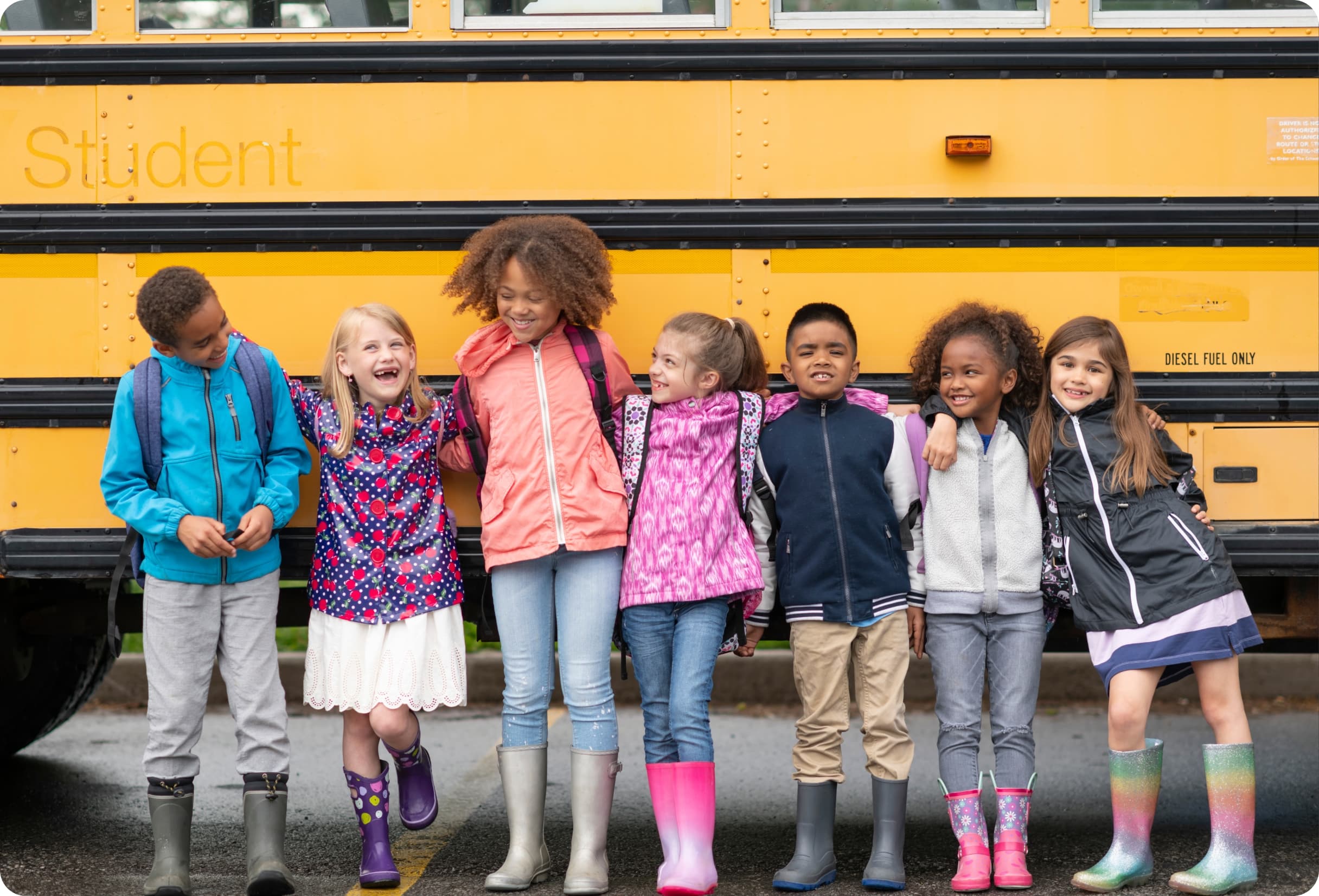 Diverse group of children in front of yellow school bus